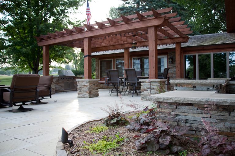 Patio kitchen - large contemporary backyard stone patio kitchen idea in Other with a pergola