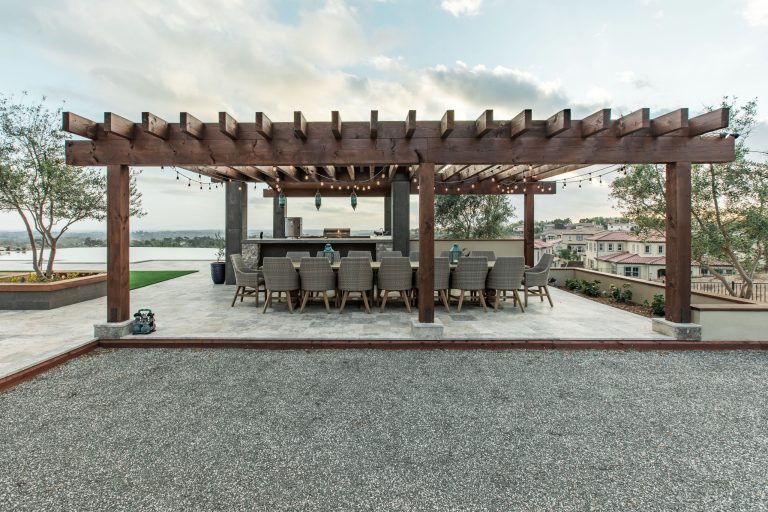 Patio kitchen - large contemporary backyard stone patio kitchen idea in San Diego with a pergola