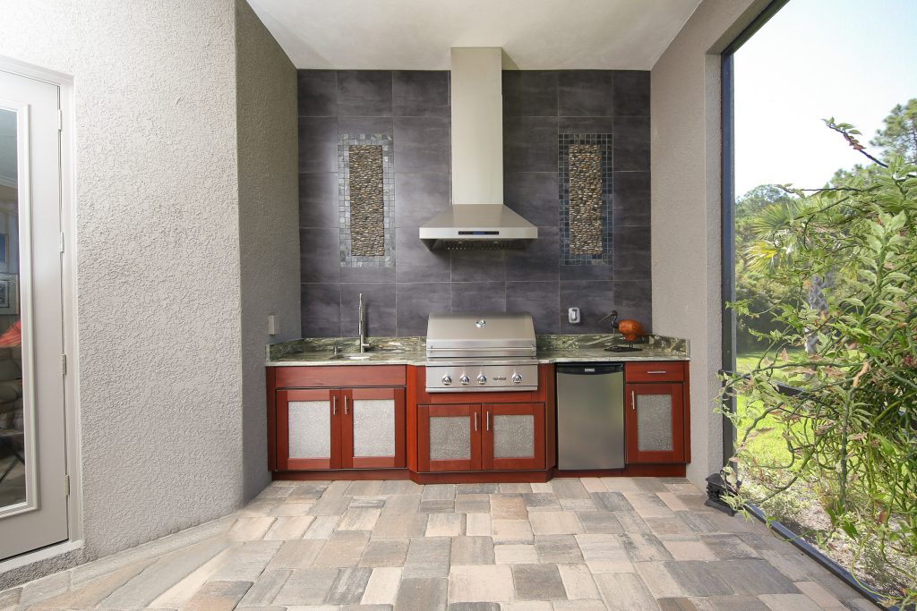 Patio kitchen - large contemporary backyard stone patio kitchen idea in Tampa with a roof extension