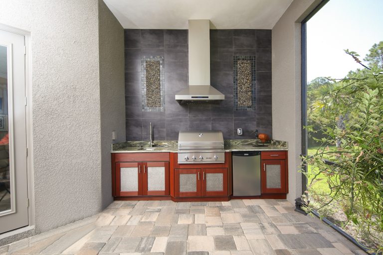 Patio kitchen - large contemporary backyard stone patio kitchen idea in Tampa with a roof extension