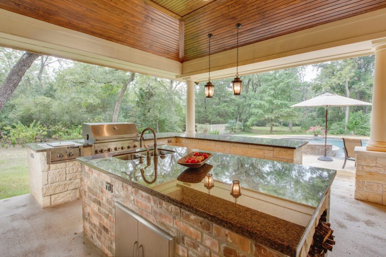 Patio kitchen - large country backyard concrete patio kitchen idea in Houston with a roof extension