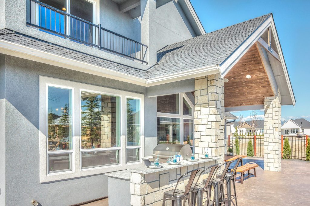 Patio kitchen - large craftsman backyard stamped concrete patio kitchen idea in Boise with a roof extension