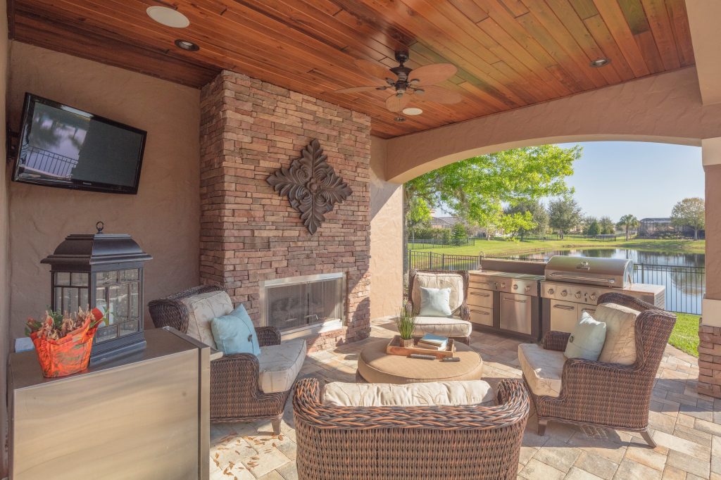 Patio kitchen - large mediterranean backyard stone patio kitchen idea in Orlando with a roof extension