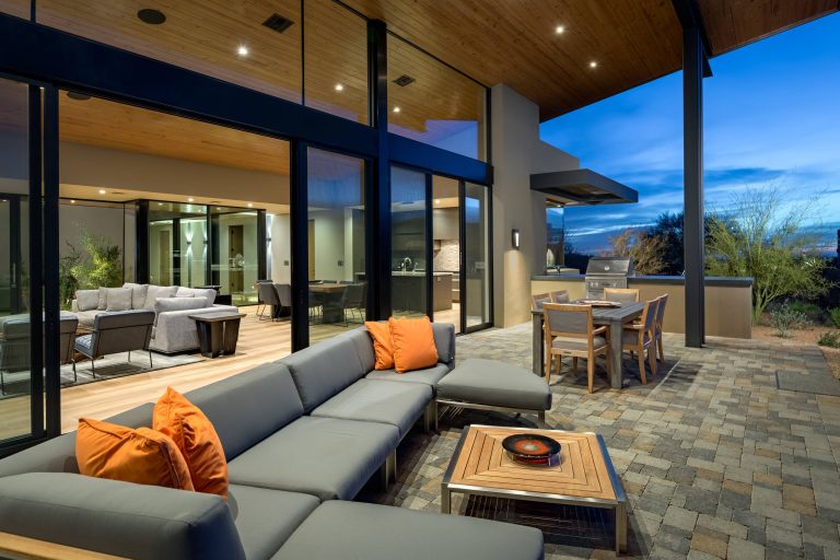 Patio kitchen - large modern backyard brick patio kitchen idea in Phoenix with a roof extension