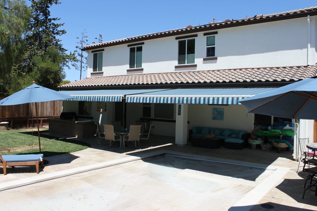 Patio kitchen - large modern backyard stone patio kitchen idea in San Francisco with an awning