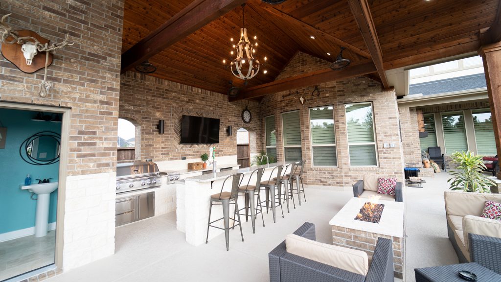 Patio kitchen - large rustic backyard concrete patio kitchen idea in Houston with a roof extension