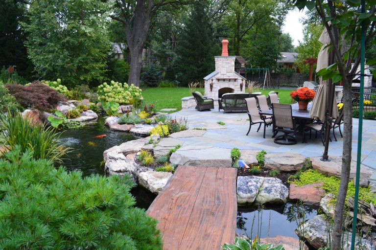 Patio kitchen - large rustic backyard stone patio kitchen idea in Chicago with no cover