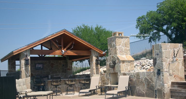 Patio kitchen - large rustic backyard stone patio kitchen idea in Dallas with an awning