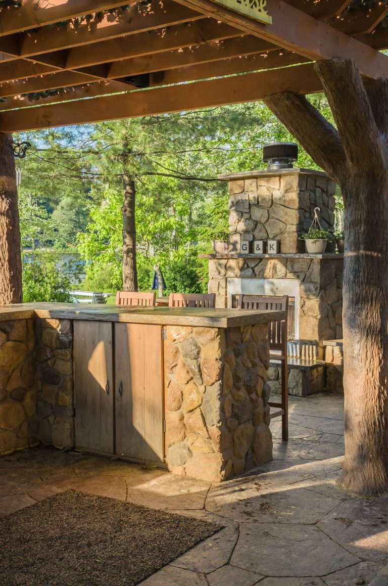 Patio kitchen - large rustic backyard stone patio kitchen idea in New York with a pergola