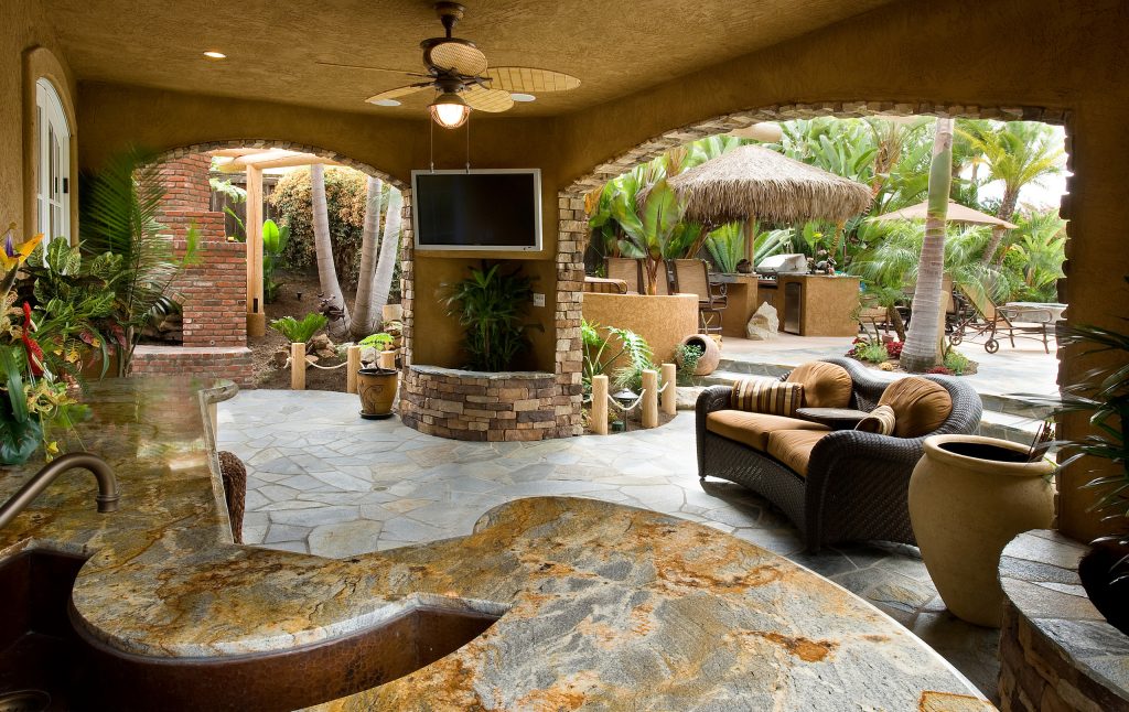 Patio kitchen - large rustic backyard stone patio kitchen idea in San Diego with a roof extension