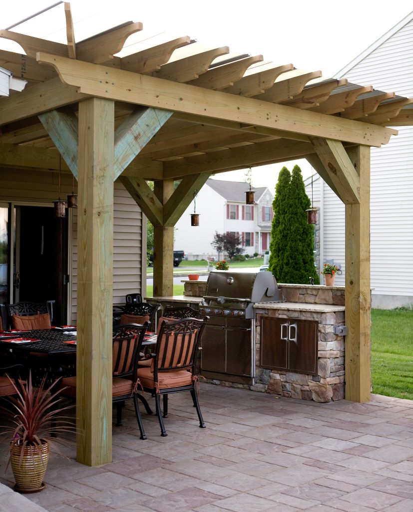 Patio kitchen - large traditional backyard concrete paver patio kitchen idea in Other with a pergola