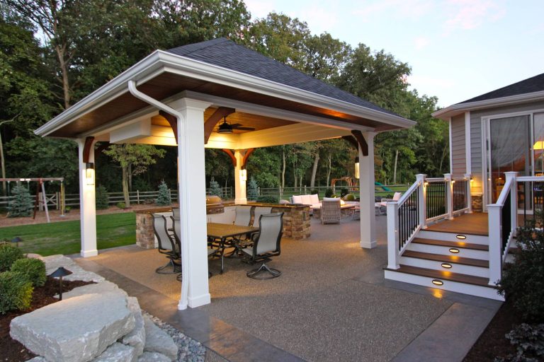 Patio kitchen - large traditional backyard stamped concrete patio kitchen idea in Other with a roof extension