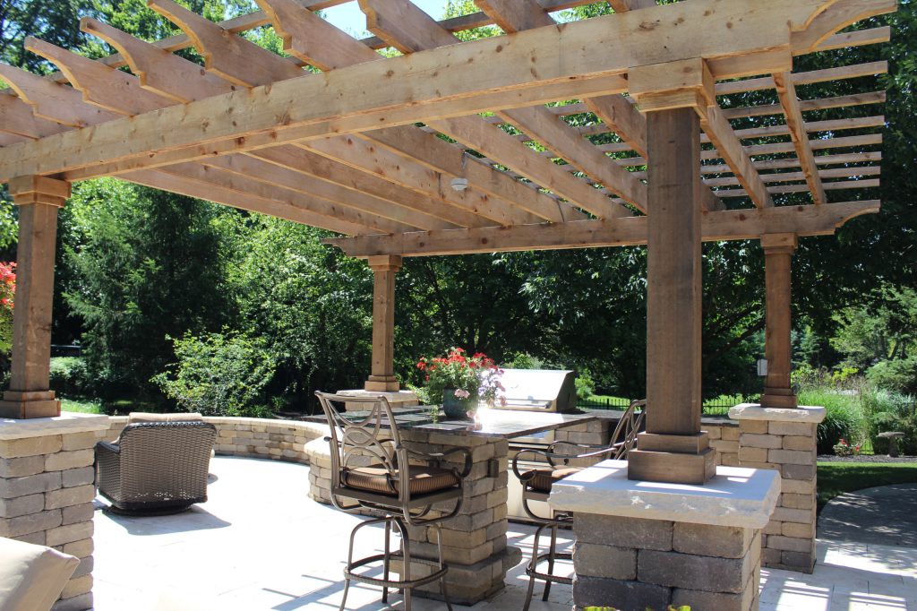 Patio kitchen - large traditional backyard stone patio kitchen idea in Indianapolis with a pergola