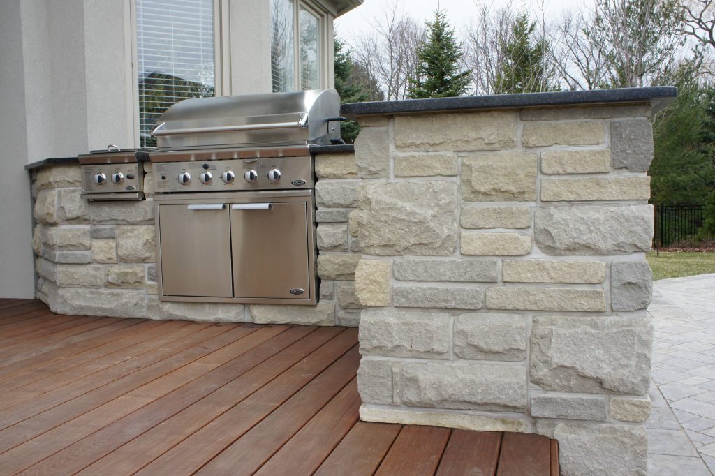 Patio kitchen - large traditional backyard stone patio kitchen idea in Orange County