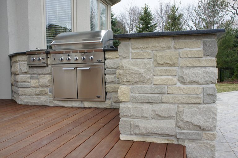 Patio kitchen - large traditional backyard stone patio kitchen idea in Orange County