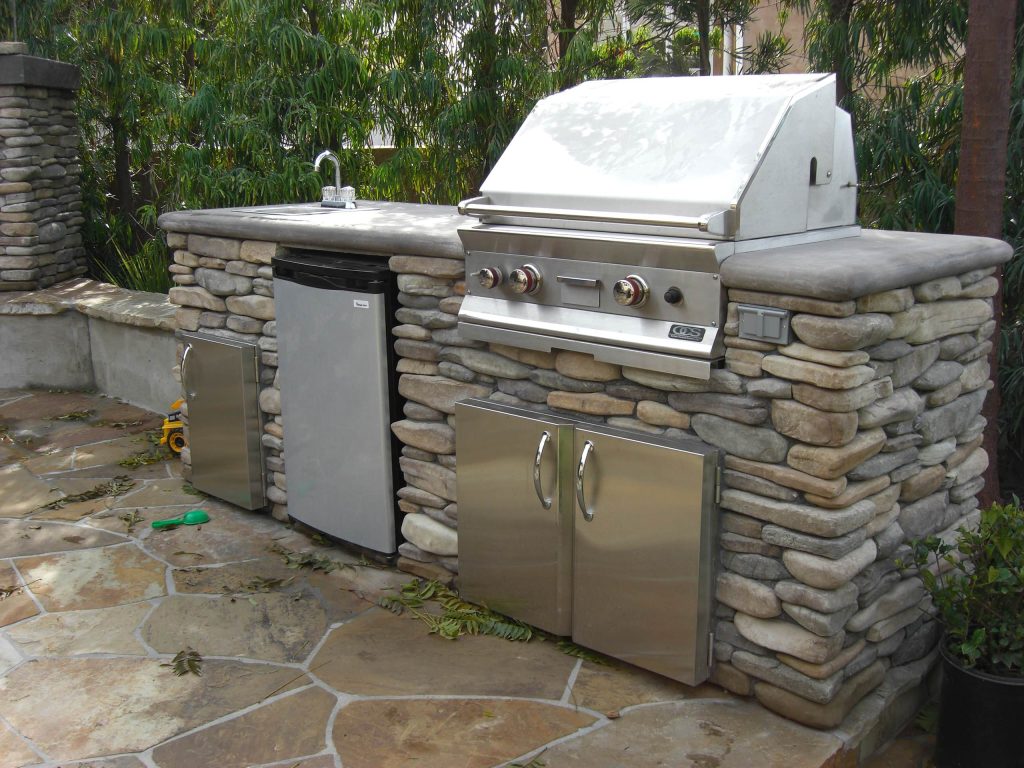 Patio kitchen - large traditional stone patio kitchen idea in Los Angeles with no cover