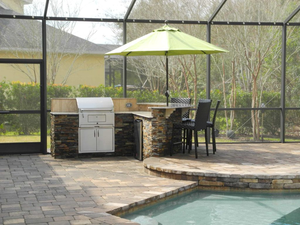 Patio kitchen - large transitional backyard concrete paver patio kitchen idea in Jacksonville with an awning