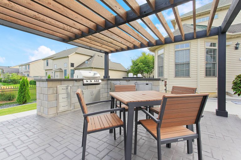 Patio kitchen - large transitional backyard stamped concrete patio kitchen idea in Chicago with a pergola