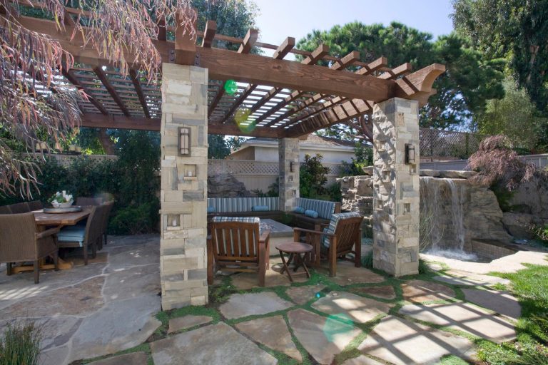 Patio kitchen - mid-sized backyard stone patio kitchen idea in Los Angeles with a pergola