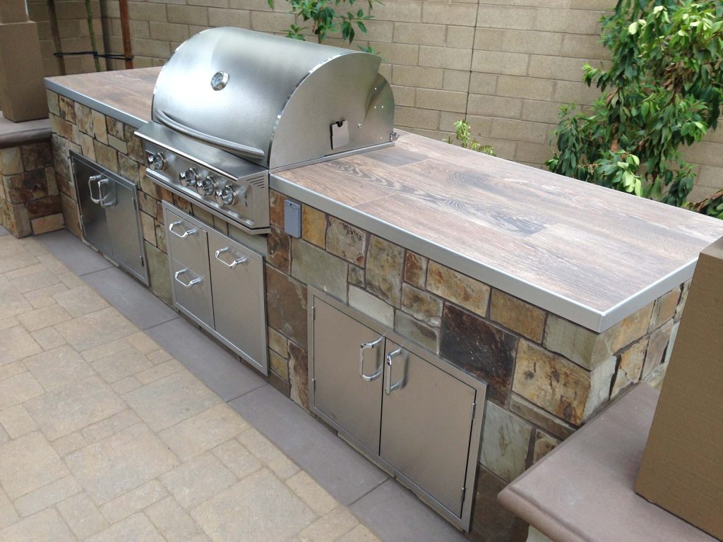 Patio kitchen - mid-sized contemporary backyard stone patio kitchen idea in Orange County with a roof extension