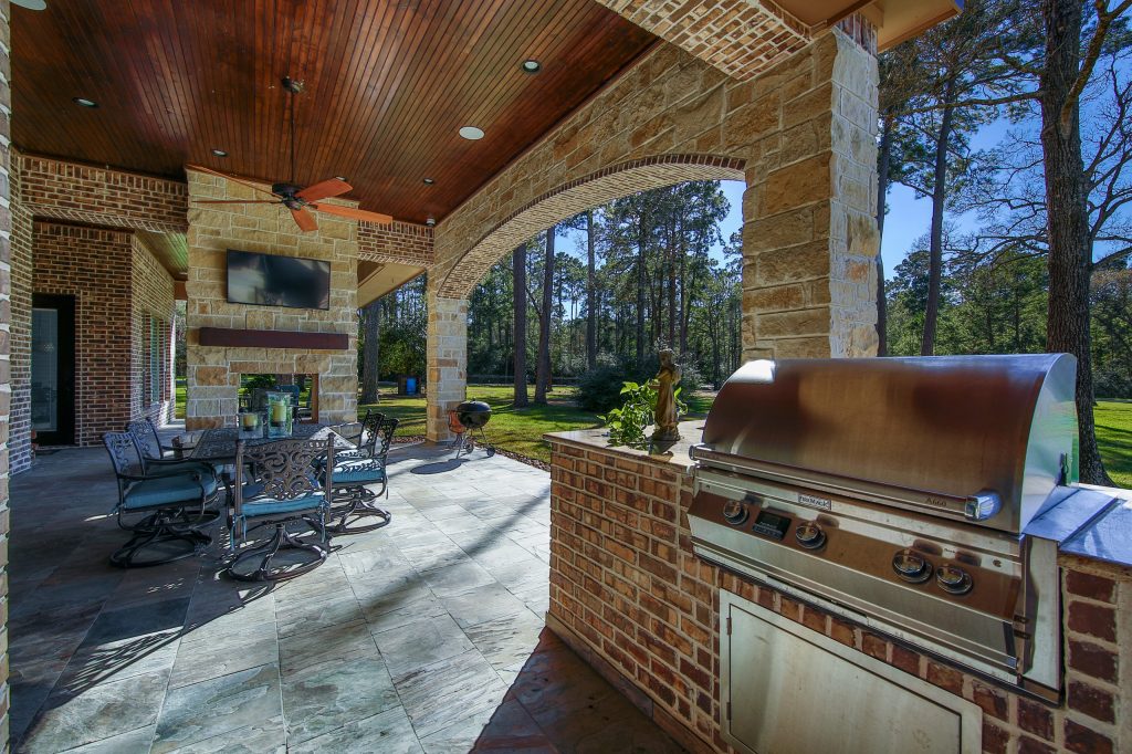 Patio kitchen - mid-sized rustic backyard stone patio kitchen idea in Houston with a roof extension