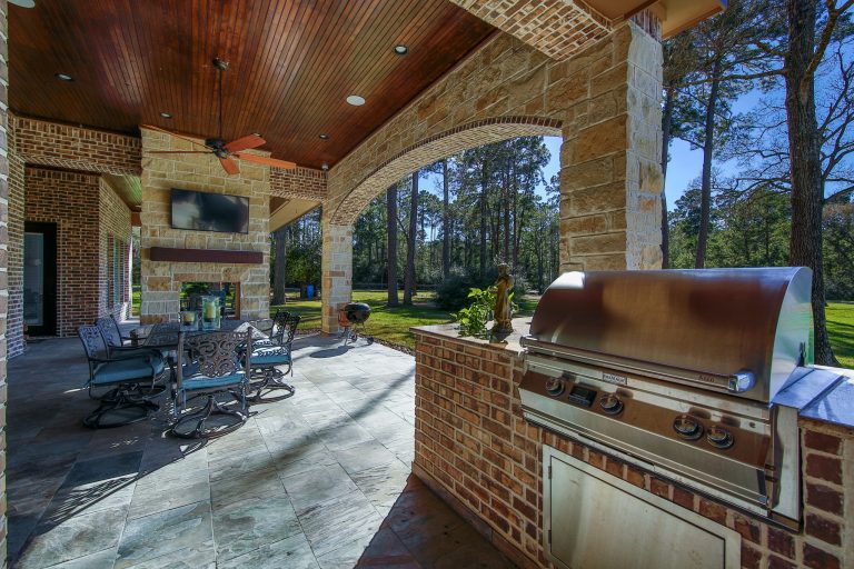 Patio kitchen - mid-sized rustic backyard stone patio kitchen idea in Houston with a roof extension