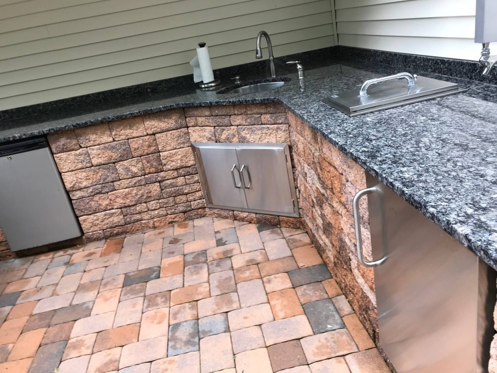 Patio kitchen - mid-sized transitional backyard brick patio kitchen idea in New York with an awning