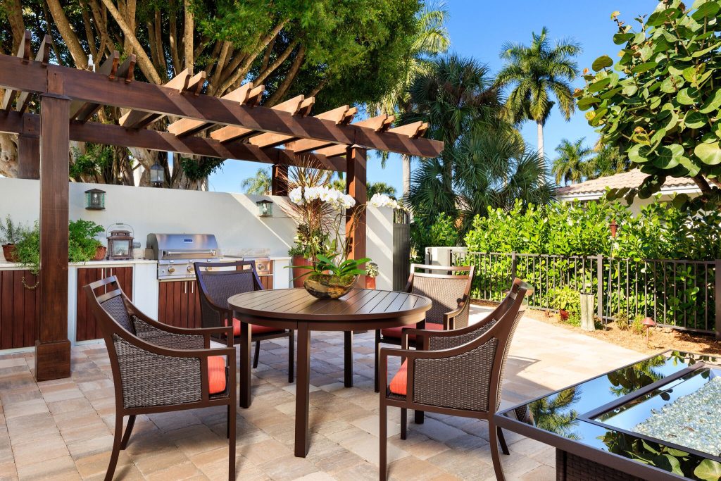 Patio kitchen - mid-sized transitional backyard stone patio kitchen idea in Miami with a pergola
