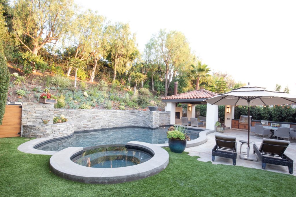 Patio kitchen - modern backyard stone patio kitchen idea in Orange County with a pergola