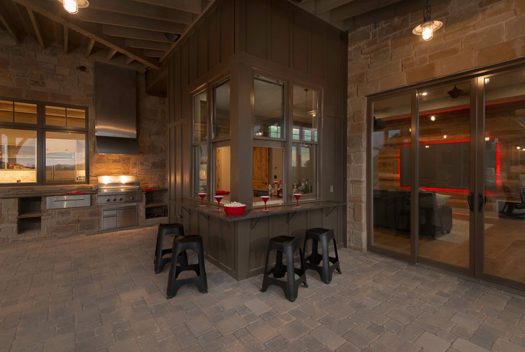 Patio kitchen - rustic backyard stone patio kitchen idea in Austin with a roof extension