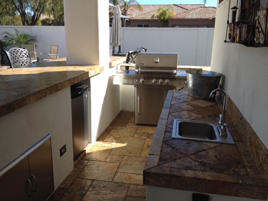 Patio kitchen - small backyard stamped concrete patio kitchen idea in Phoenix with a roof extension