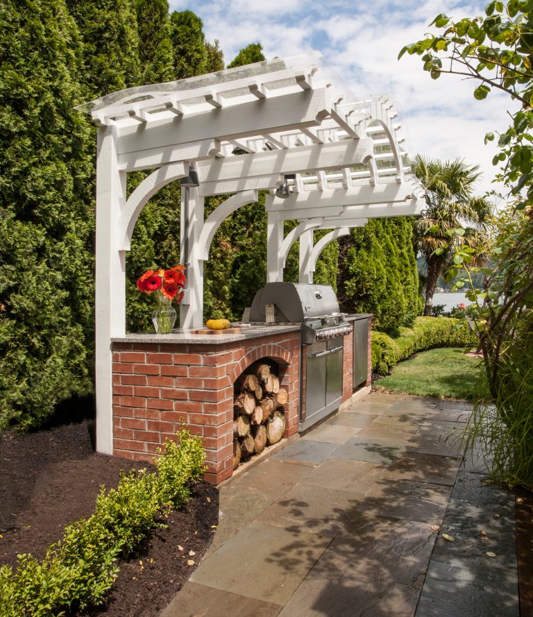 Patio kitchen - small traditional backyard stone patio kitchen idea in Seattle with a pergola