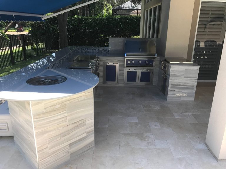Patio kitchen - tropical backyard stone patio kitchen idea in Miami with an awning