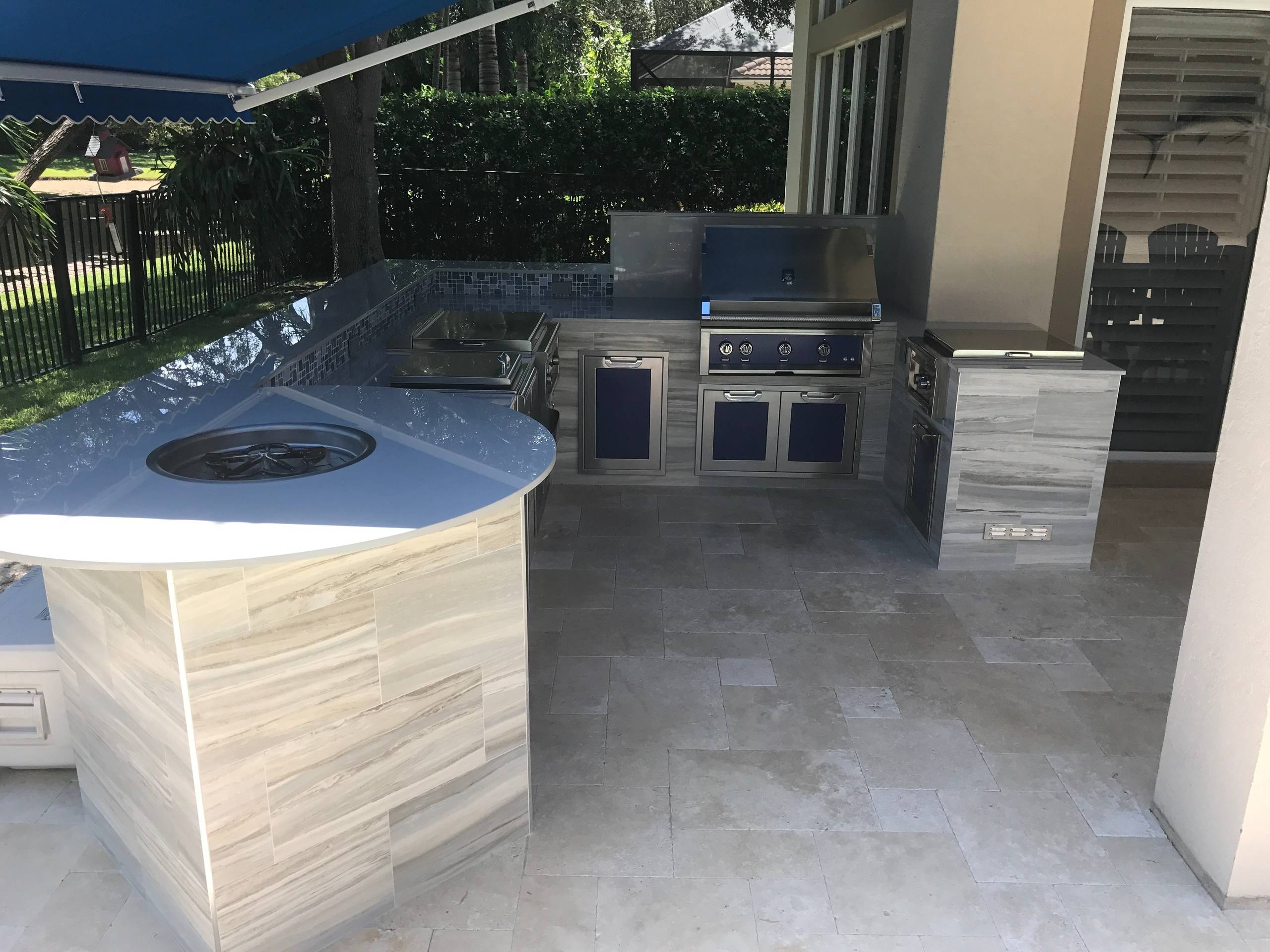 Patio kitchen – tropical backyard stone patio kitchen idea in Miami with an awning