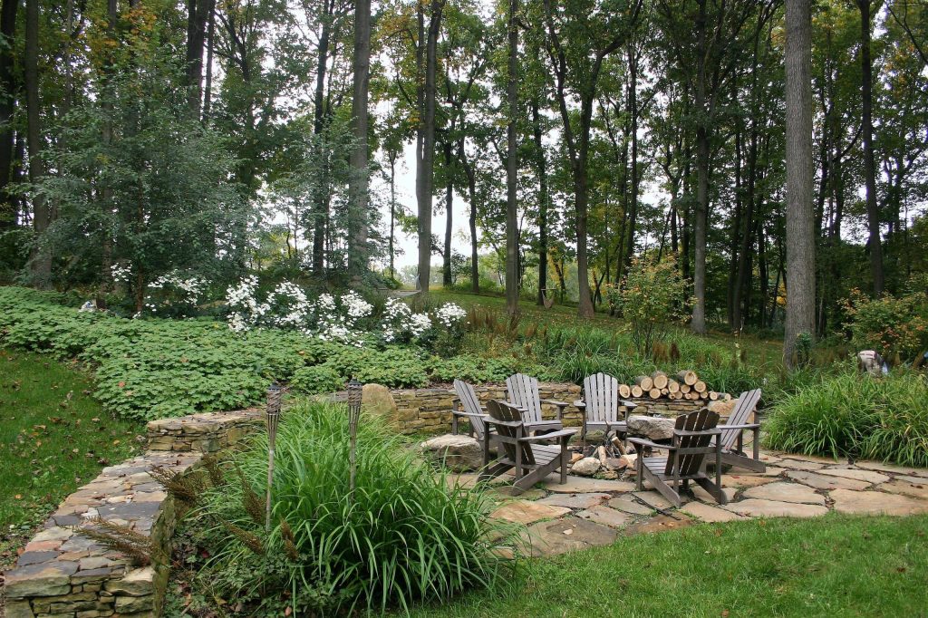 Photo of a large rustic partial sun backyard stone formal garden in Philadelphia with a fire pit.