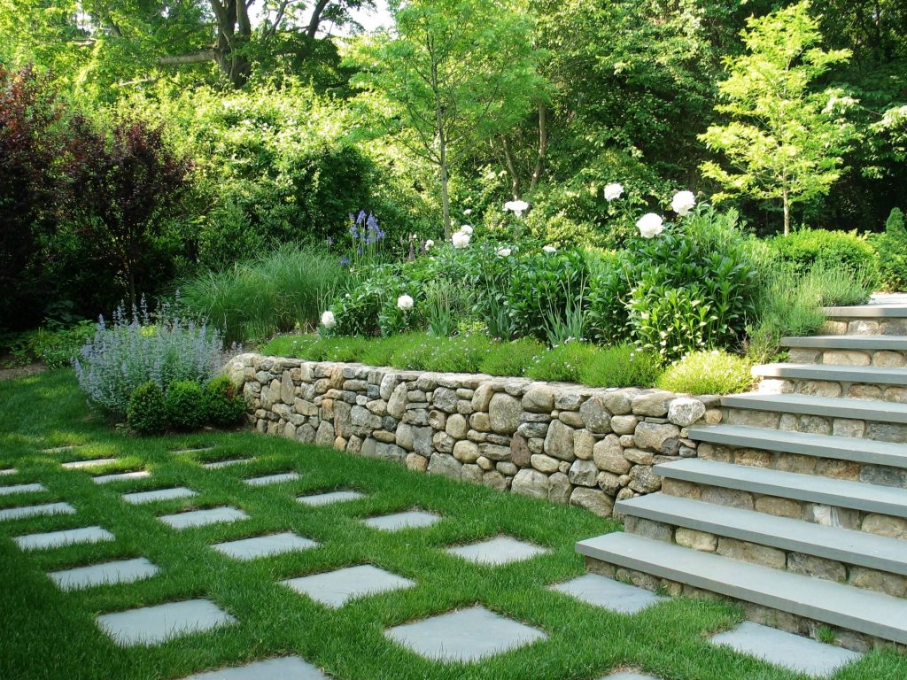 Photo of a large traditional partial sun backyard stone retaining wall landscape in New York.