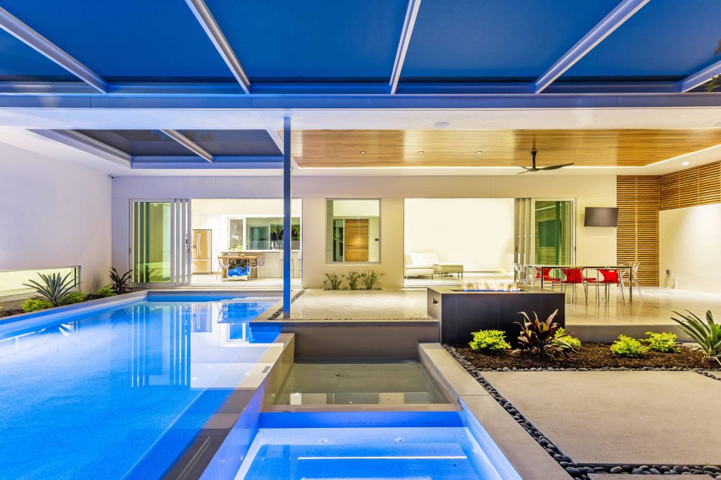 Pool area with sunken spa and reflecting pond, outdoor fireplace, polished concrete covered patio, cypress ceiling, cypress rain screen, polished concrete coping and etched concrete pads. Ryan Gamma Photography