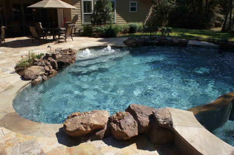 Pool fountain - large tropical backyard concrete paver and custom-shaped pool fountain idea in Houston