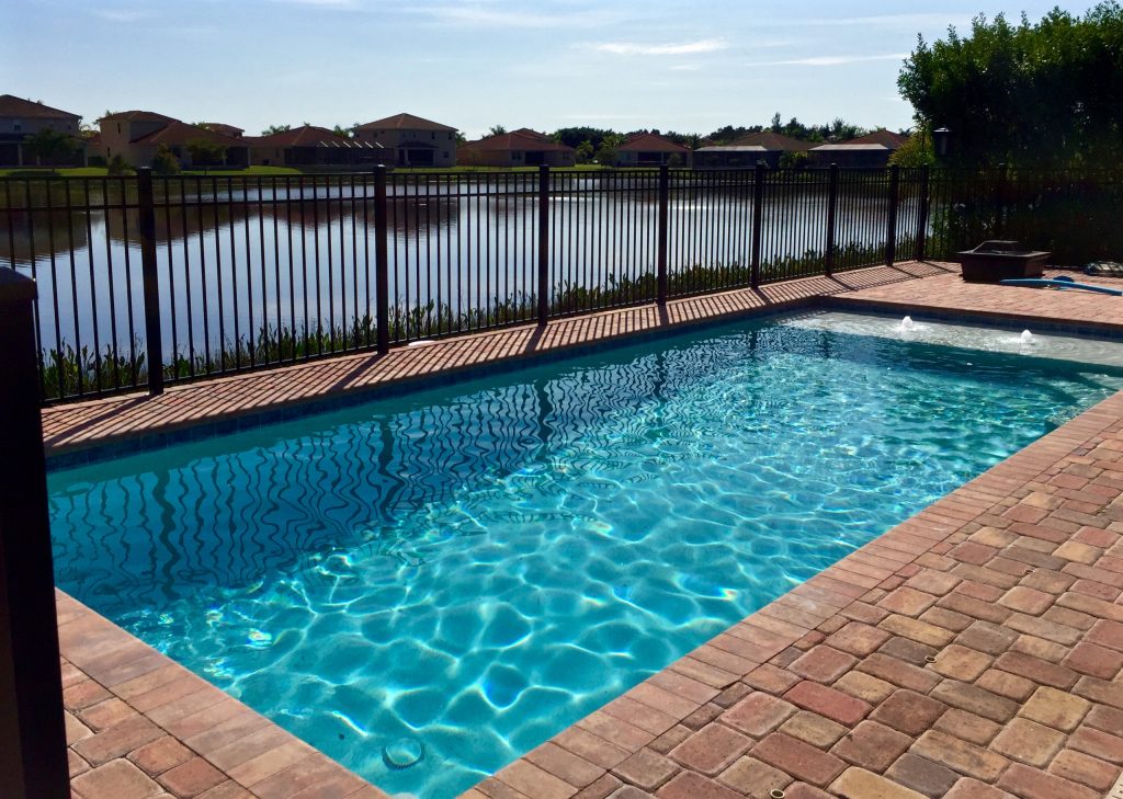 Pool fountain - small tropical backyard brick and rectangular pool fountain idea in Miami
