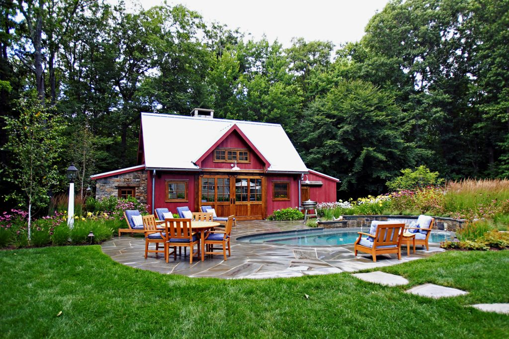Pool house - mid-sized cottage backyard stone and round lap pool house idea in New York