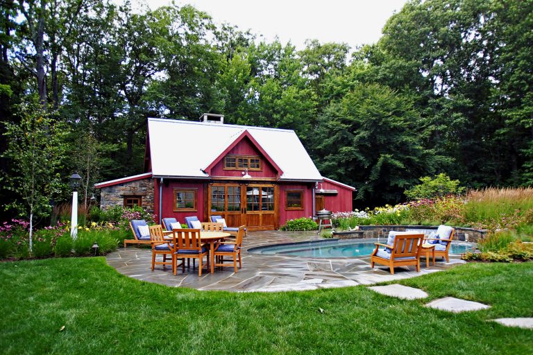 Pool house - mid-sized cottage backyard stone and round lap pool house idea in New York
