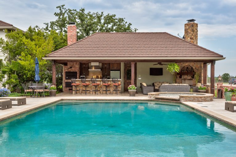 Pool house with rock bar, island and fireplace. Brick smoker and custom cabinetry. Photo Credits: Epic Foto Group