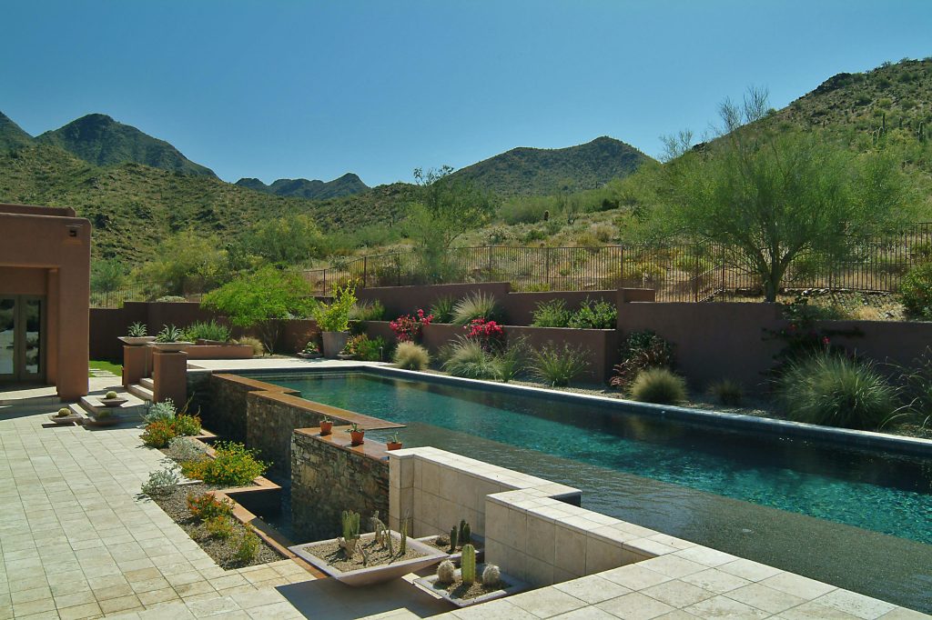 Pool - mid-sized mediterranean backyard stone and rectangular infinity pool idea in Phoenix