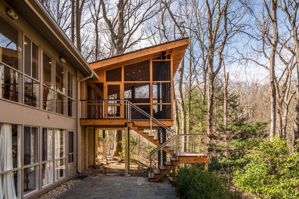 Rear screened porch with wood-burning fireplace and additional firewood storage within mantel.