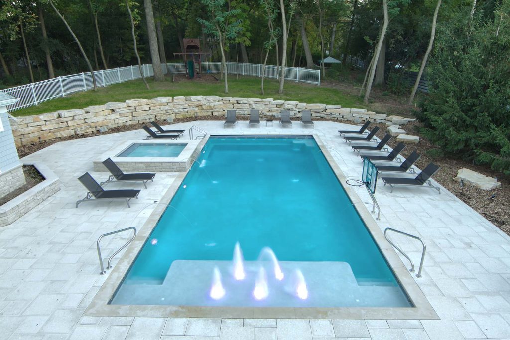 Request Free Quote Pool and spa with a waterfall, water jets, and a sun shelf.