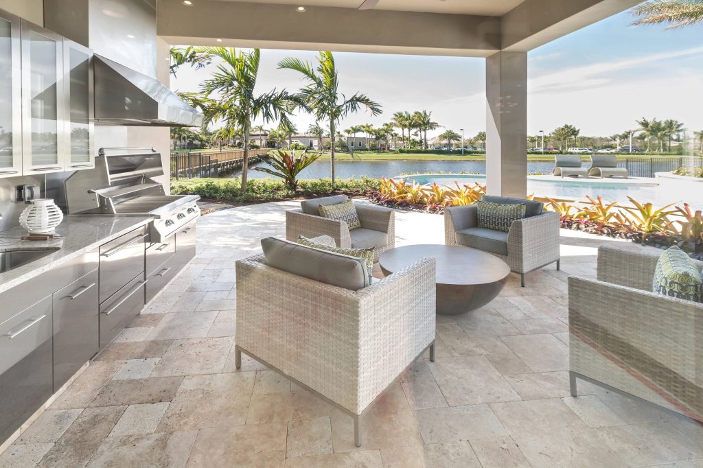 Resort community outdoor kitchen and terrace with Janus et Cie furnishings. Table custom designed by JCRD Group. Floors are tumbled travertine. Custom fabricated stainless steel outdoor cabinetry.
