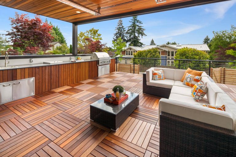 Roofed deck with outdoor kitchen and seating area with parquet flooring.