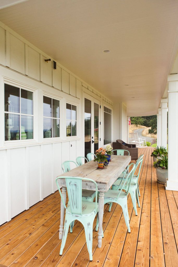 Rustic outdoor living table and chairs on a covered, wraparound porch.