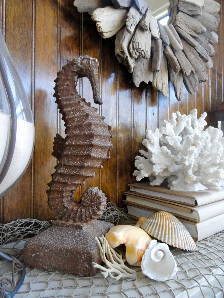 Rusty Seahorse leant great curves to break up the straight lines of the paneling. An inexpensive fish net goes a long way to adding texture and interest as well. by Charissa English | Outdoor Photos | Porch | Landscaping | Landscape Design | Outdoor Living Space | Porch Design Ideas | Outdoor Living Space Ideas | Backyard Design