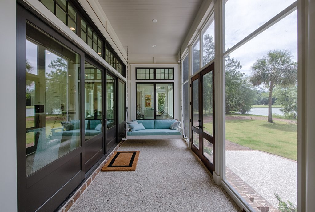 Screened back porch with bed swing, tabby floor, and 12-ft sliding doors that open to the living room.